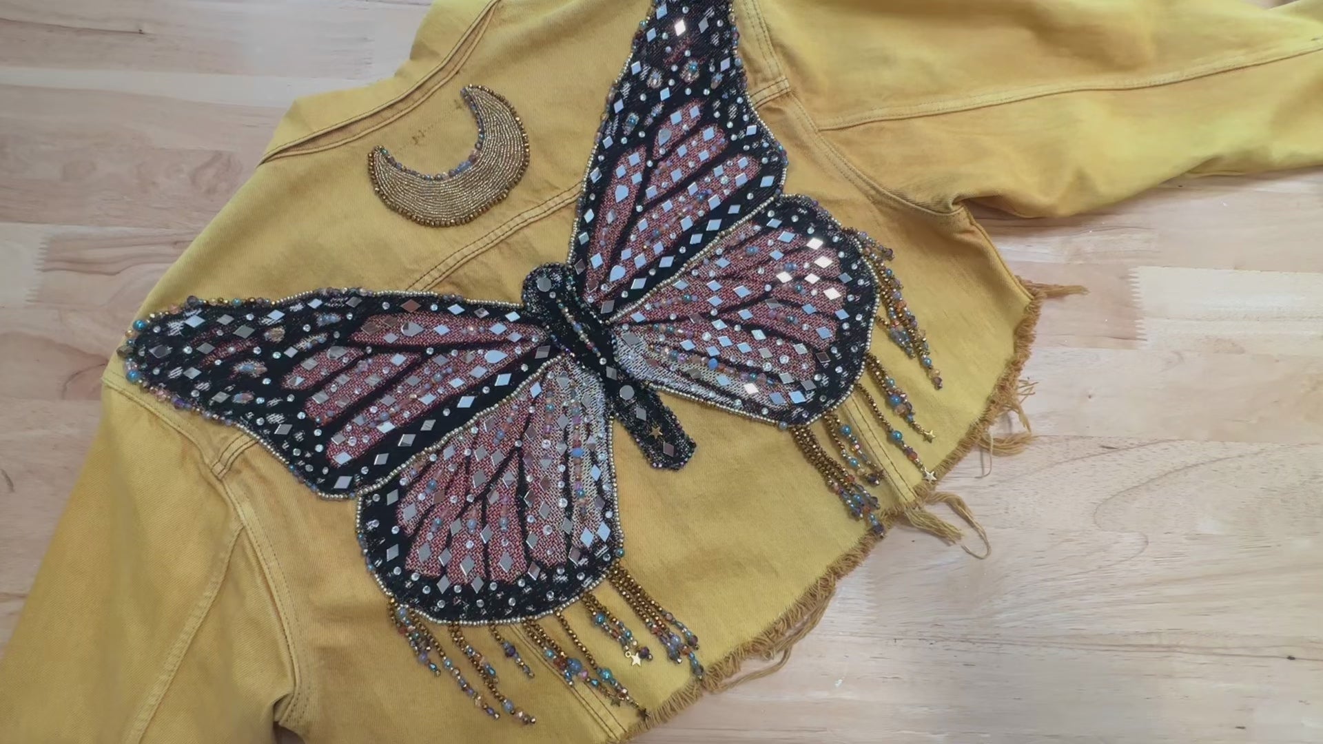 Load video: video of yellow butterfly jacket with tiny mirrors with a beaded crescent moon