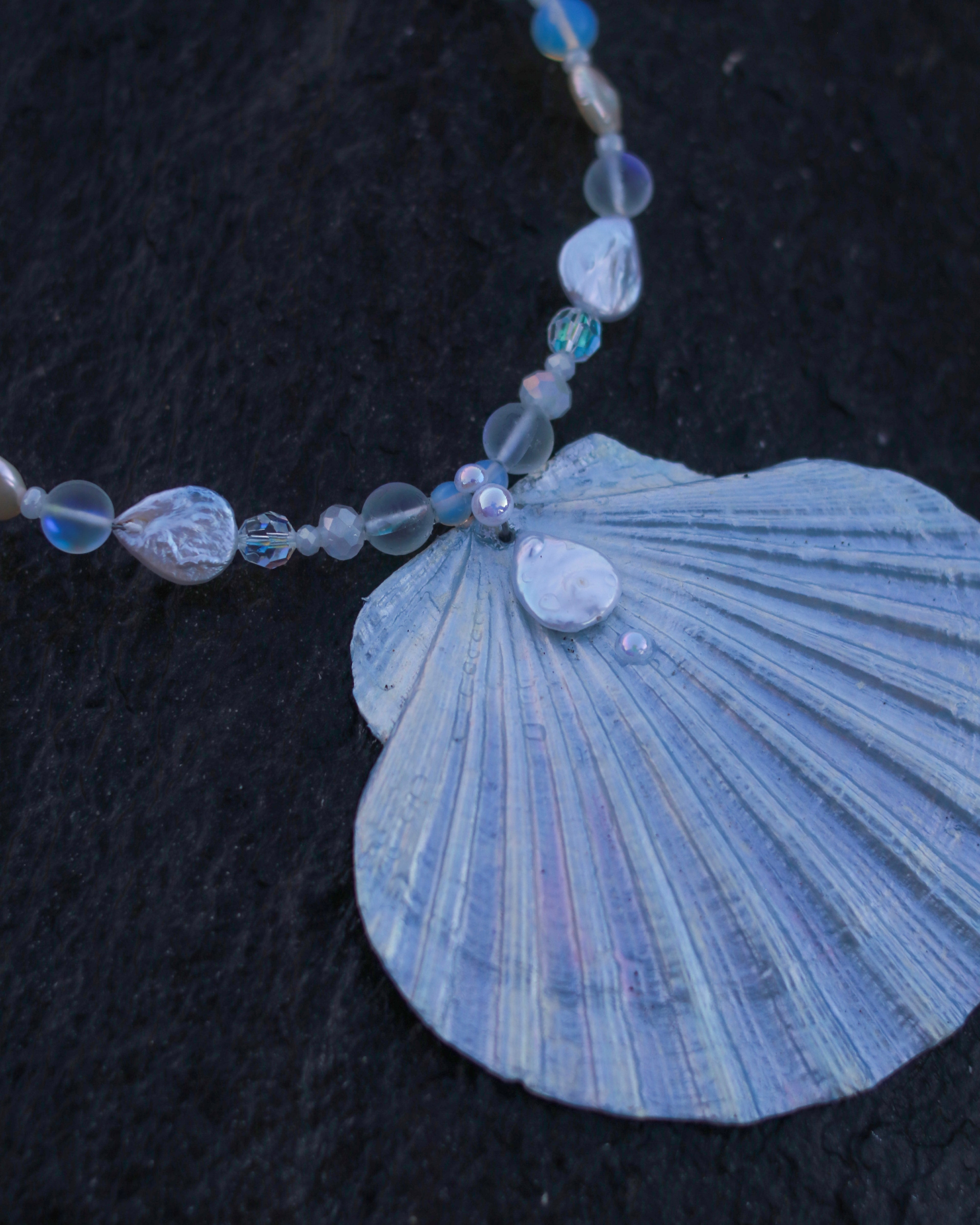 Necklace with blue shell pendant and beads on a dark background