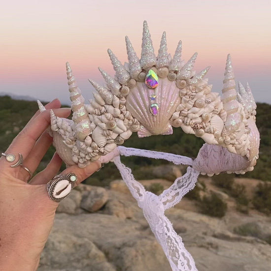 video of a seashell headband being held up against the sky at sunset