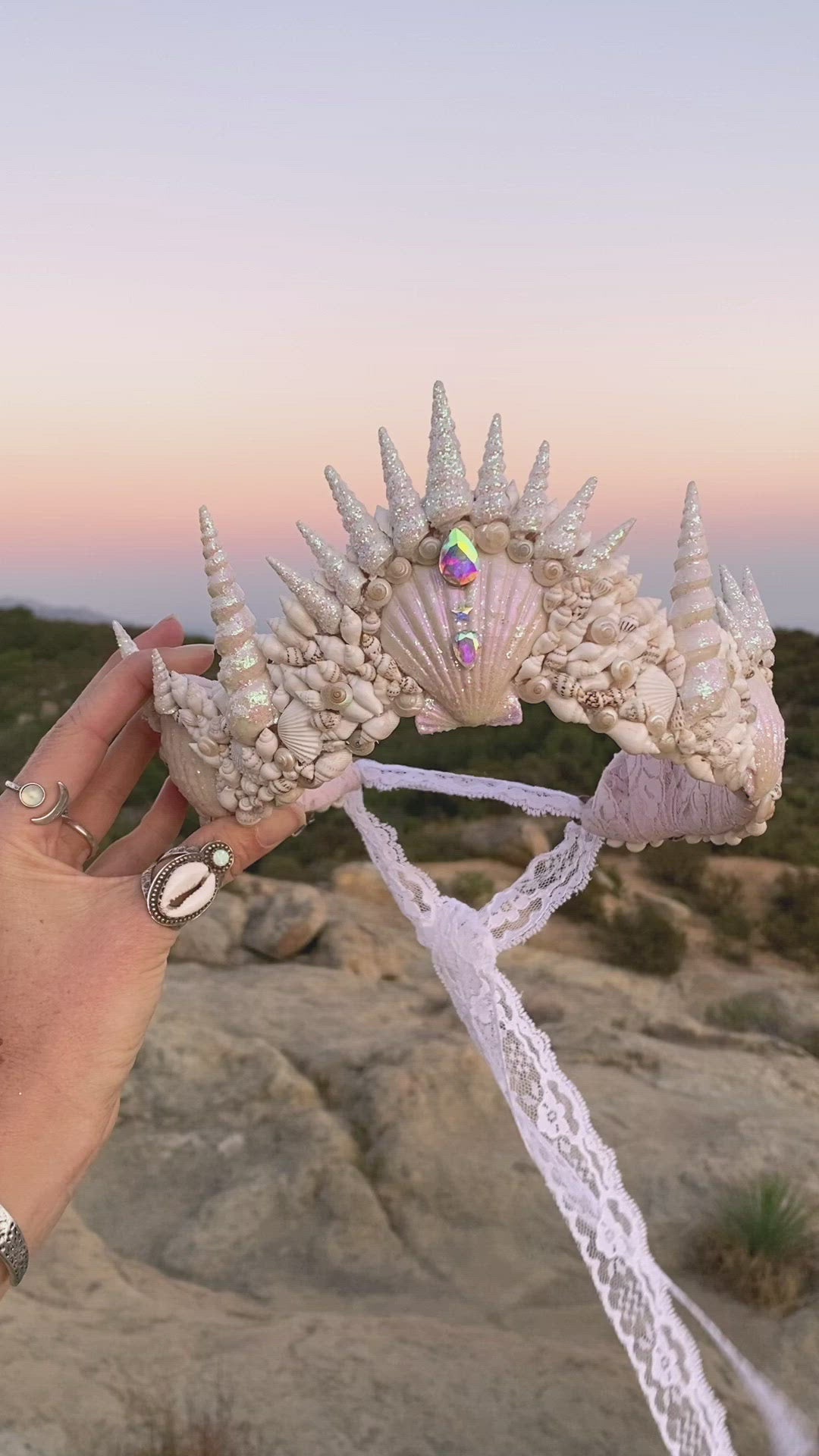 video of a seashell headband being held up against the sky at sunset
